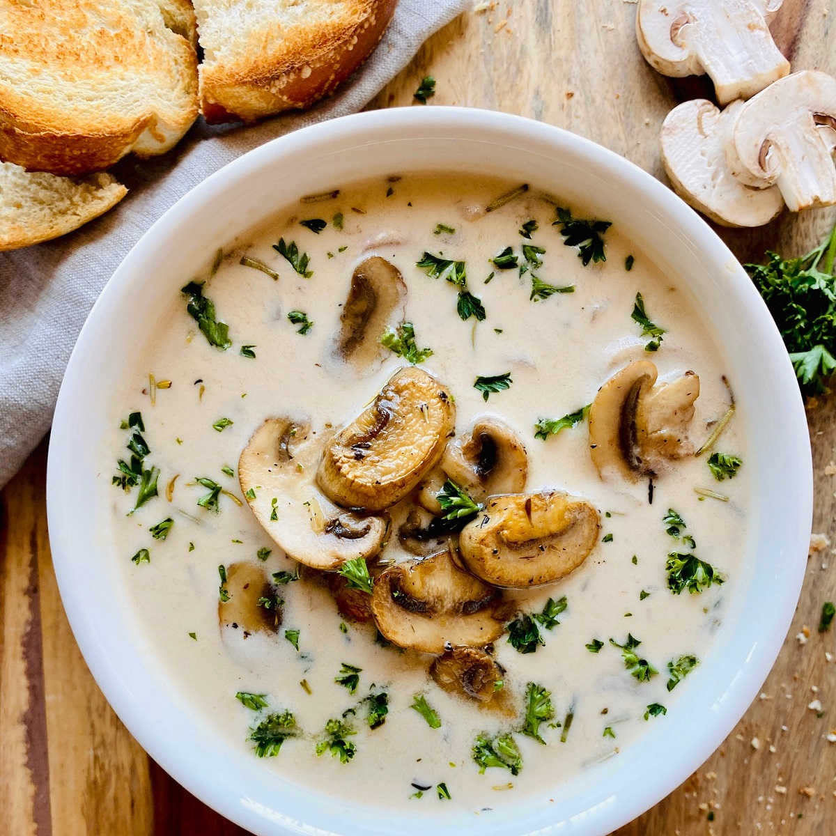 healthy mushroom soup in white bowl next to crusty bread