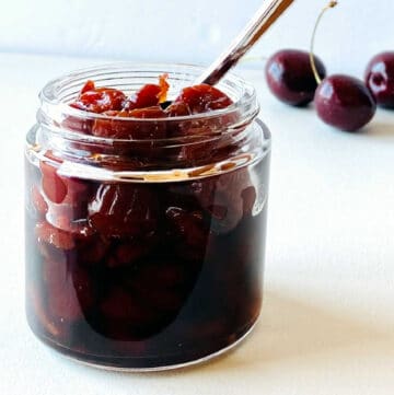 jar of bourbon cherries with cherries in background