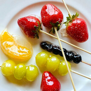 tanghulu fruit strawberries grapes blueberries orange slice on white plate