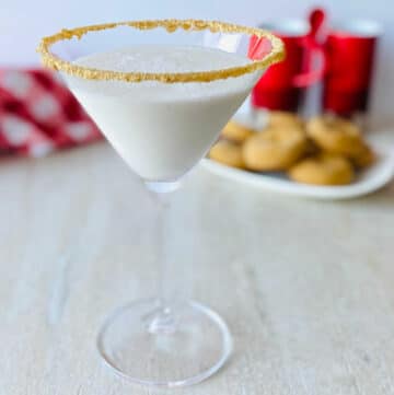 Gingerbread Martini Christmas Cocktail in martini glass with gingerbread cookies in the background