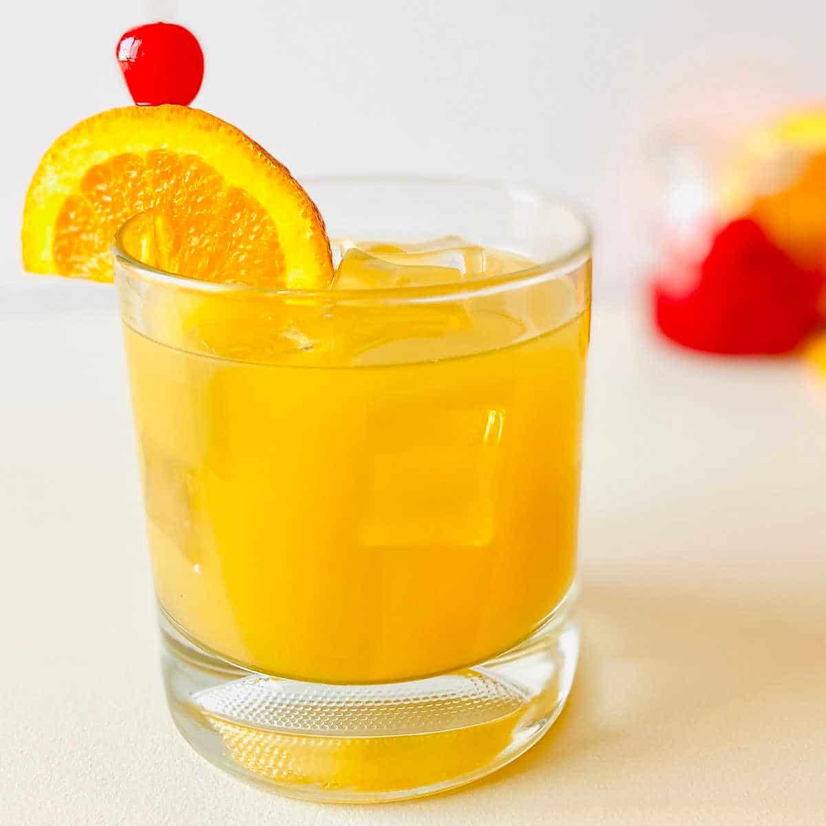 whiskey sour mocktail in rocks glass garnished with orange and cherry
