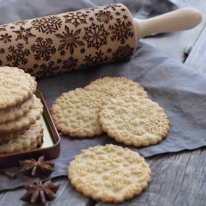 embossed rolling pin next to baked cookies with imprinted snowflakes