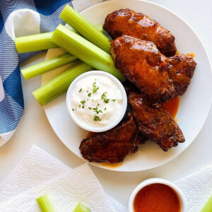 air fryer chicken wings on a plate next to celery and blue cheese