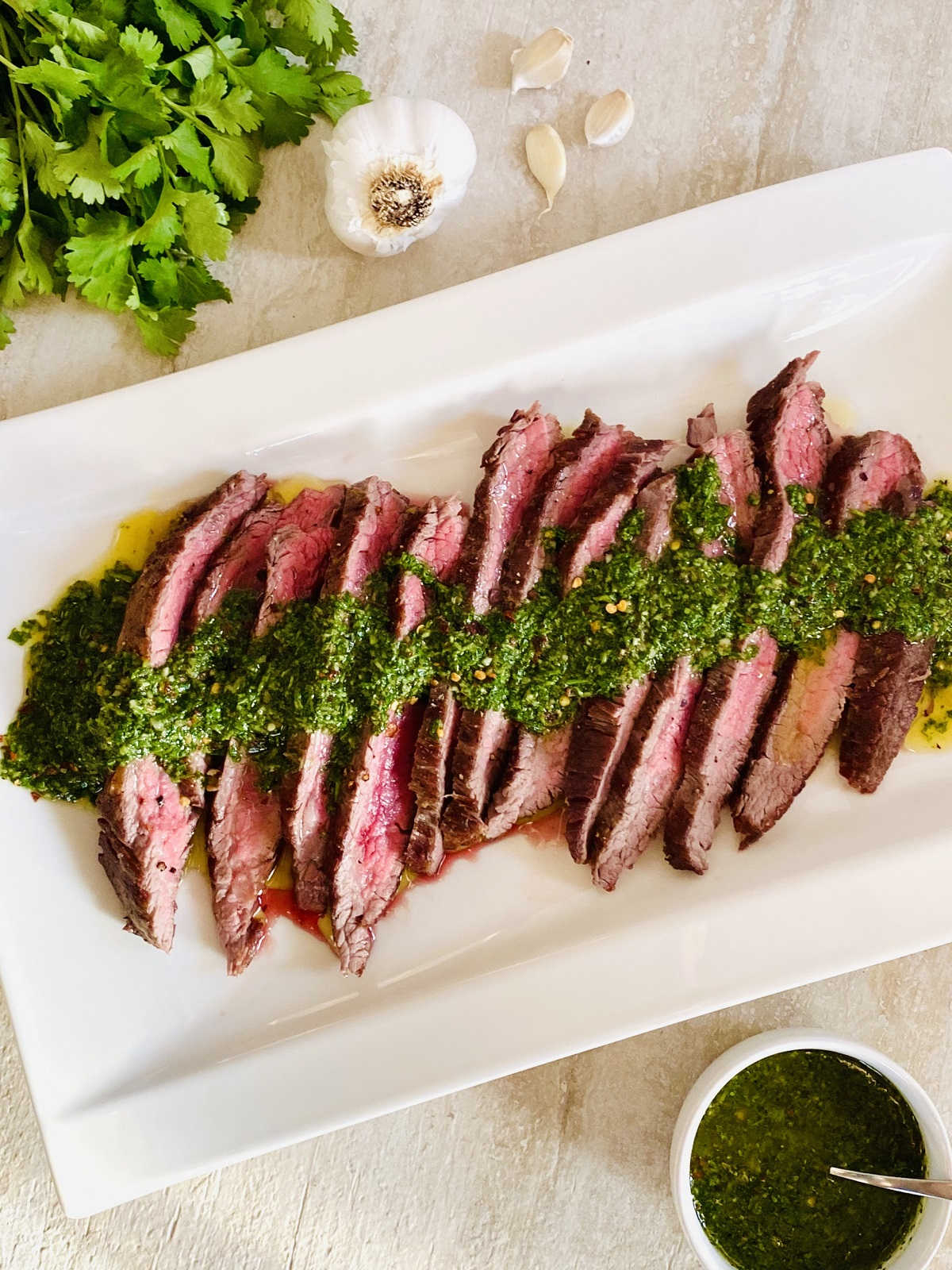 sliced bavette steak on plate topped with chimichurri