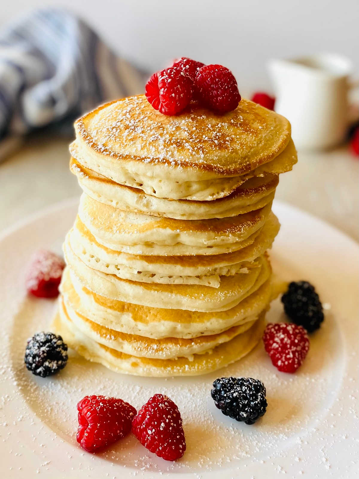 almond milk pancakes in a stack on a plate topped with raspberries