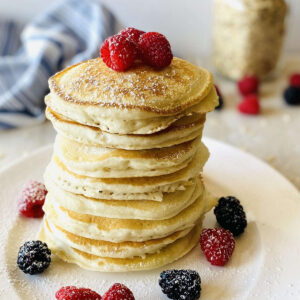 oat flour pancakes on a plate topped with fresh berries