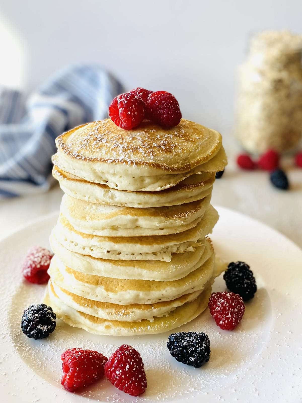 oat flour pancakes on a plate topped with fresh berries