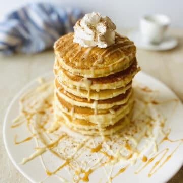 tres leches pancakes on a plate drizzled with tres leches syrup, caramel dulce de leche and whipped cream