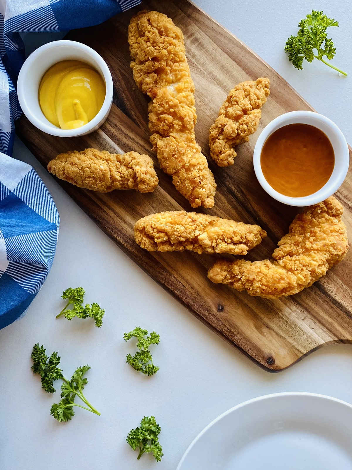 air fryer frozen chicken tenders on wooden board next to dipping sauces