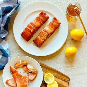 honey smoked salmon on a plate next to honey and lemons