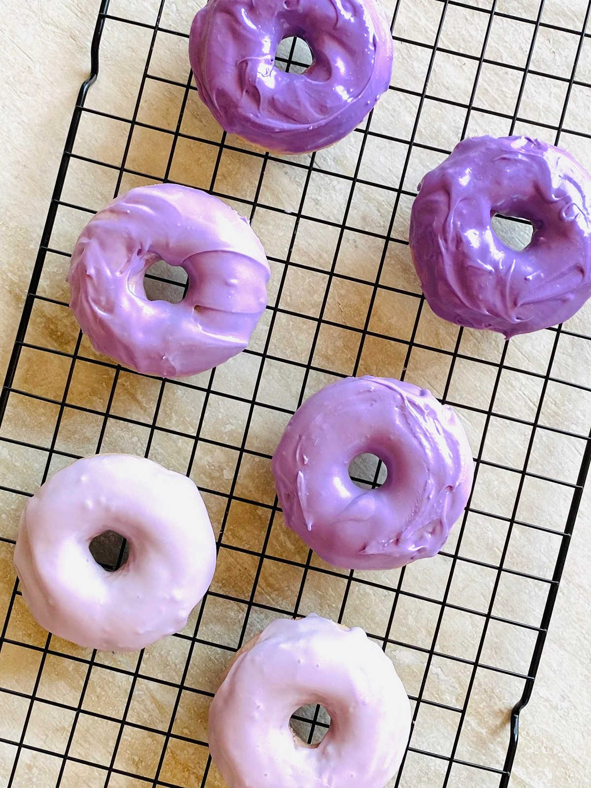 ube donuts on a baking rack
