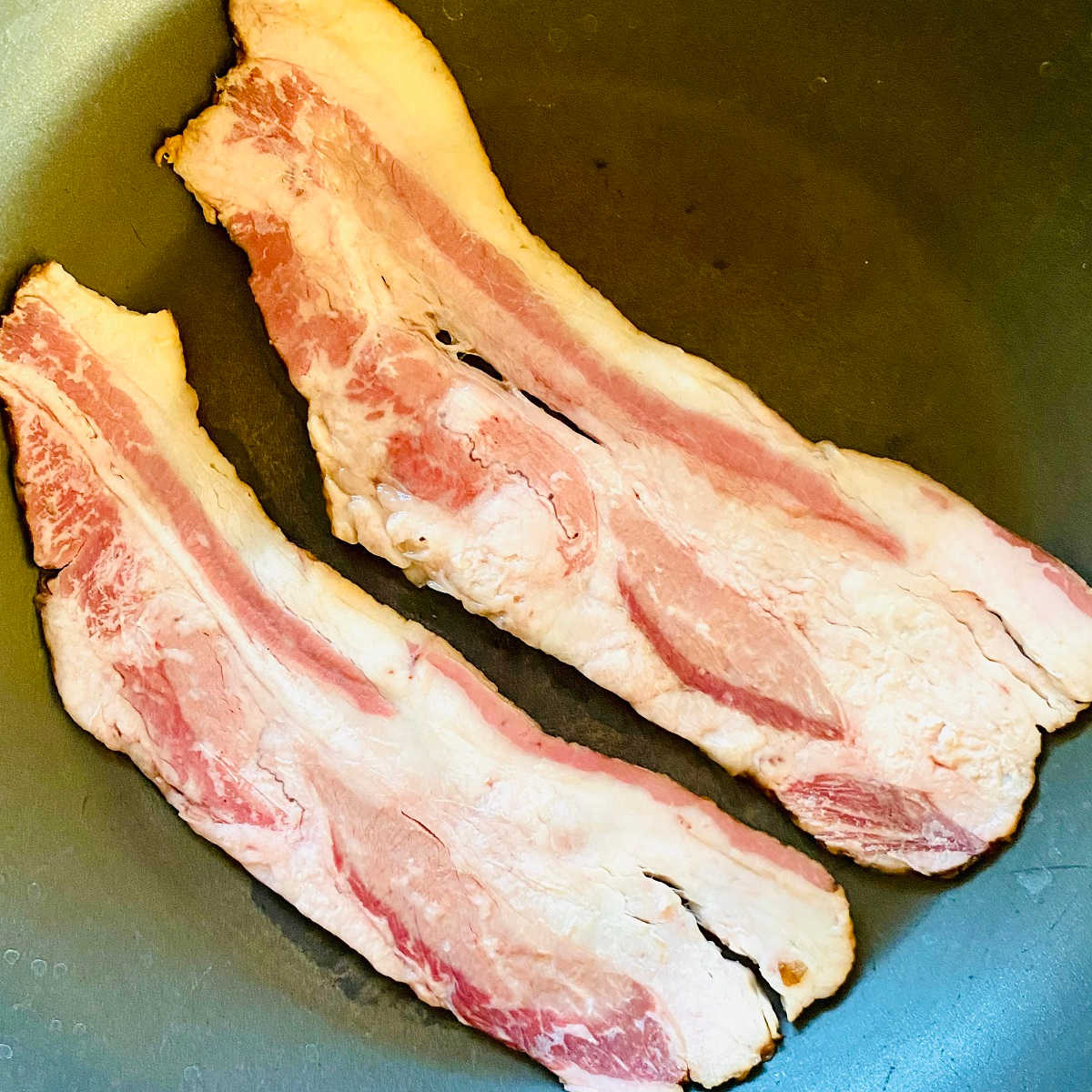 two slices of wagyu bacon in a pan