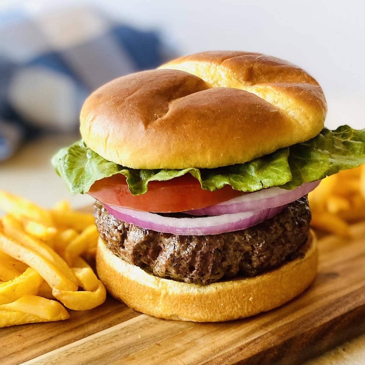 frozen burger cooked in air fryer on a bun with lettuce tomato onion and french fries