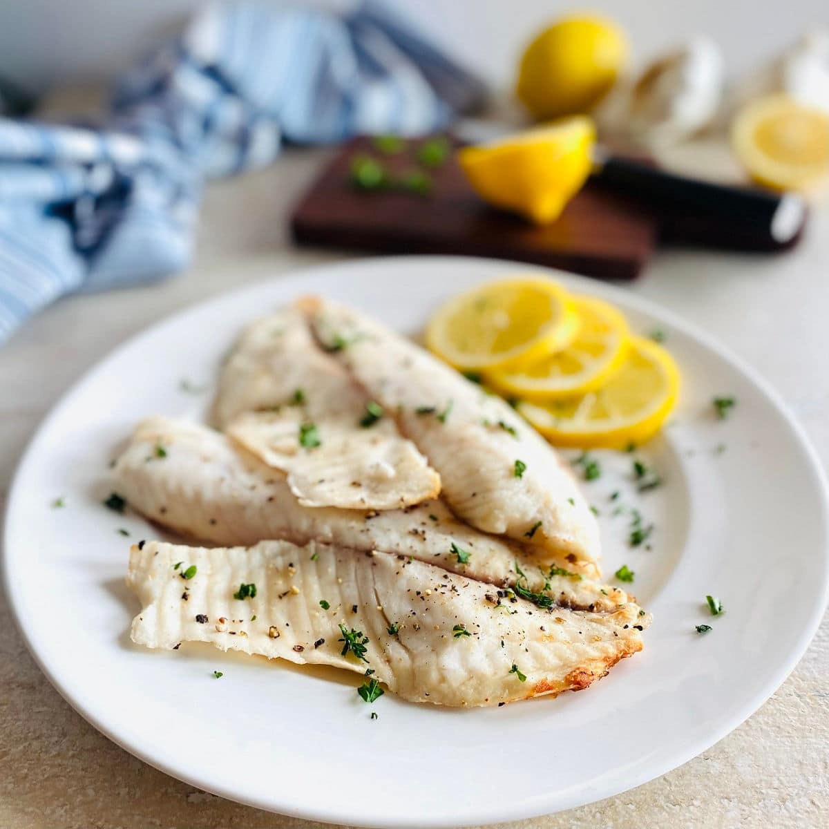 air fried tilapia on a plate with lemon and parsley