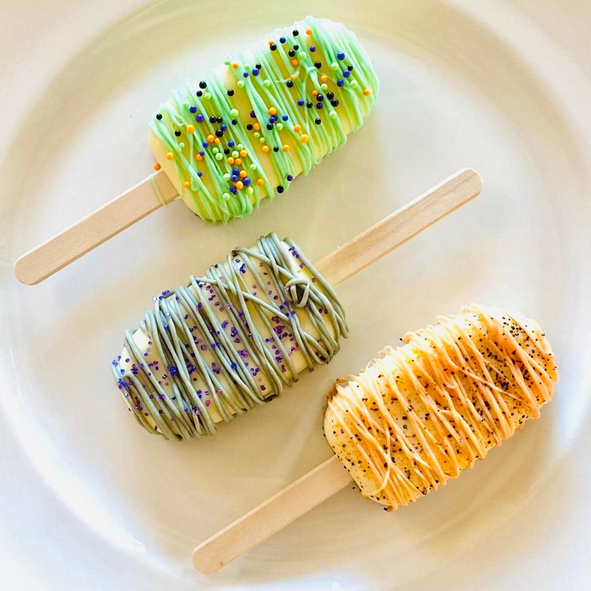 three halloween cakesicles on a plate decorated with sprinkles