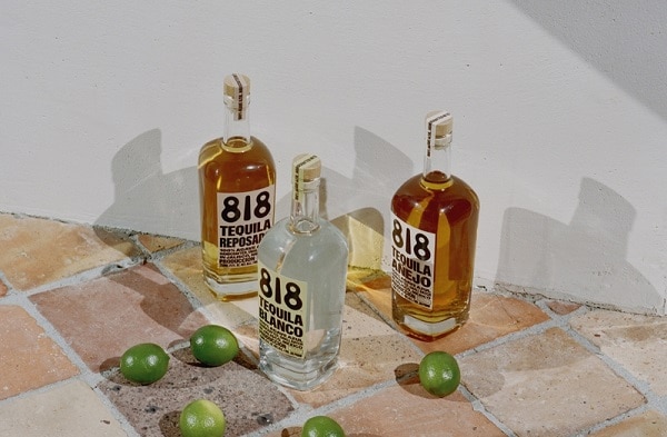 3 bottles of 818 tequila next to limes