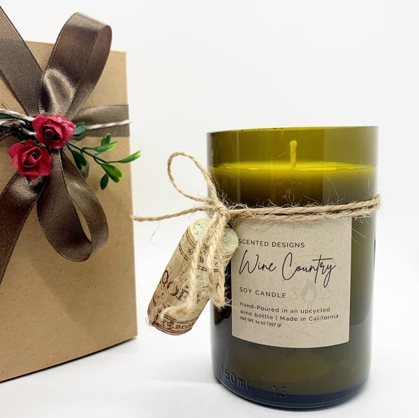 scented designs candle in upcycled wine bottle next to gift box