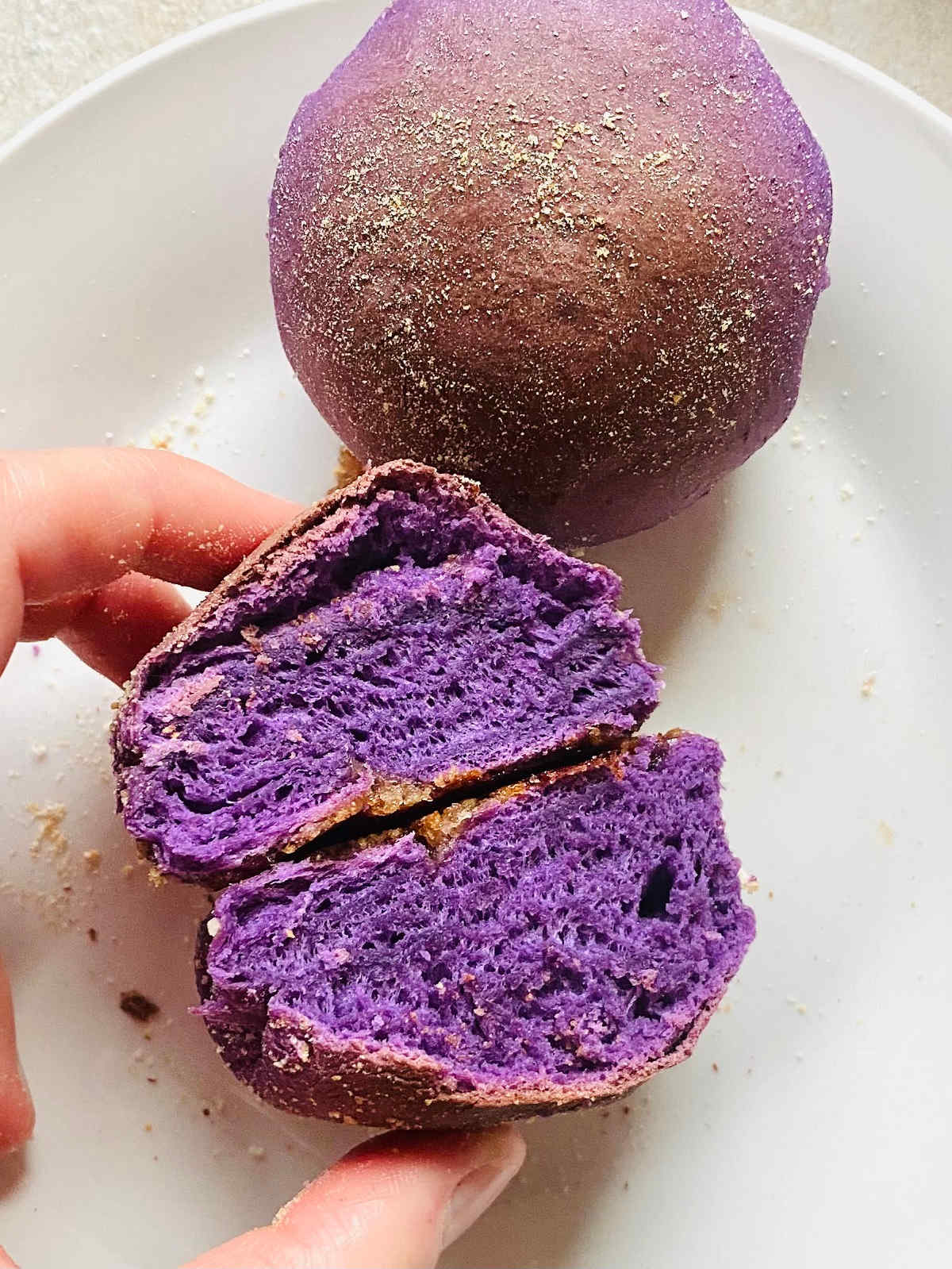 ube pandesal Filipino bread roll cut open sitting next to another uncut roll