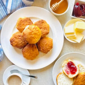 pillsbury air fryer biscuits on a plate next to honey, jam, butter and coffee
