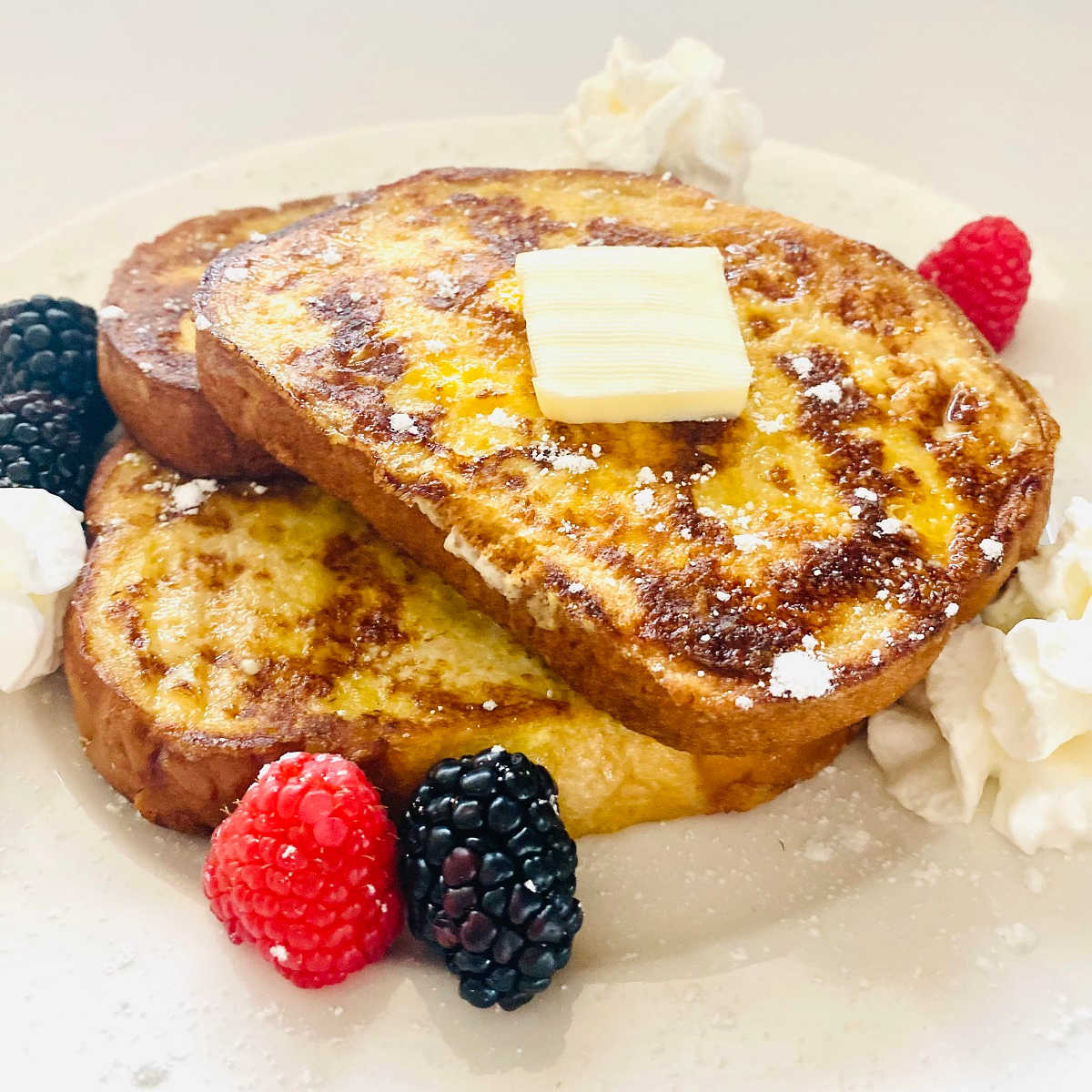 french toast recipe with sourdough bread on plate with berries and butter