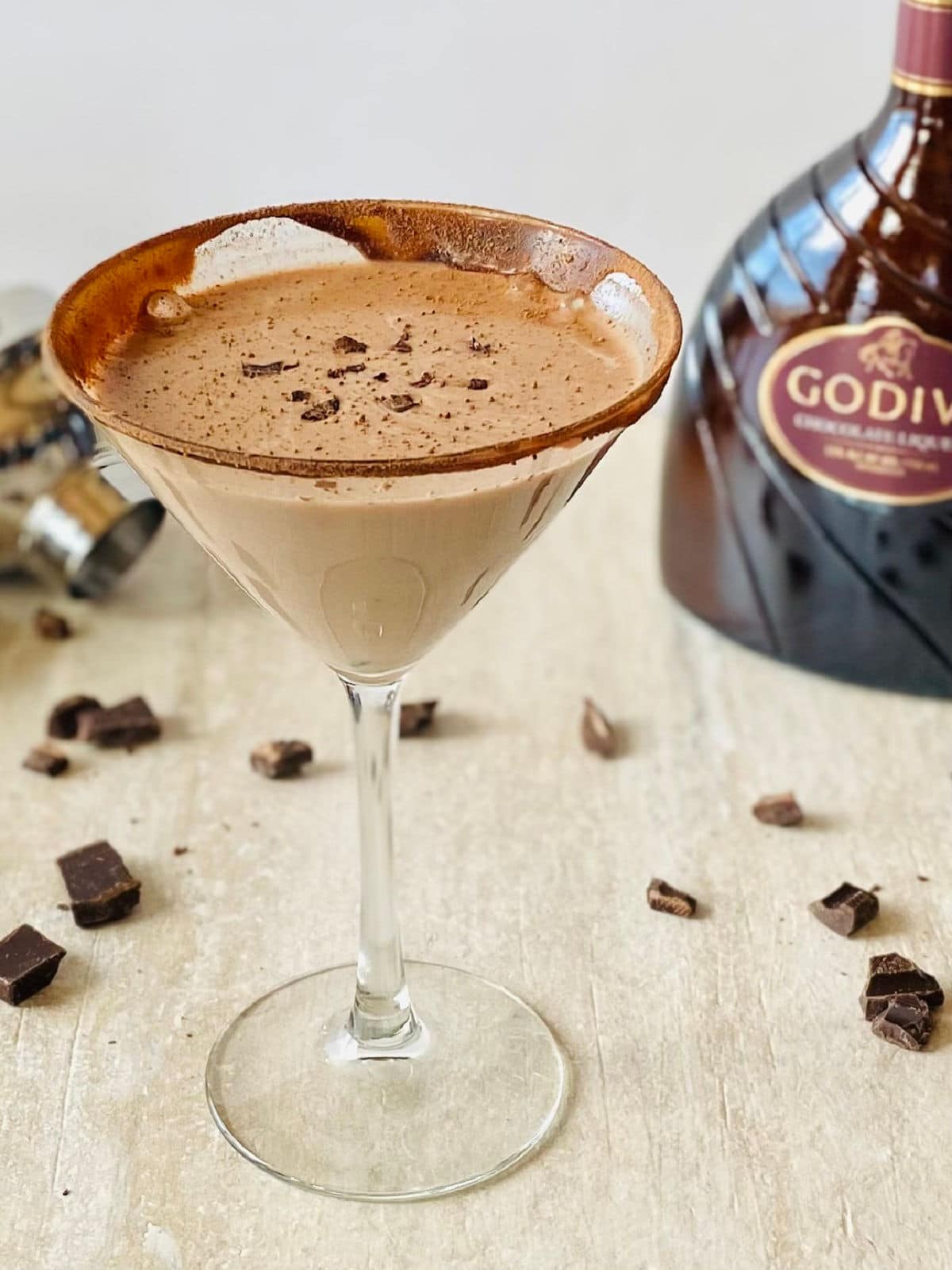 godiva chocolate martini in a martini glass with godiva liqueur in background