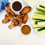 brine chicken wings next to wing sauce, ranch dressing and a plate of vegetables