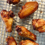 brined chicken wings deep fried resting on a cooling rack