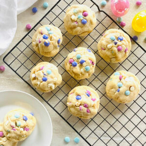 Easter cookies on a cooling rack next to colored Easter eggs and a plate of 2 Easter cookies