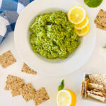 cashew basil pesto on a plate with lemon garnish and crackers