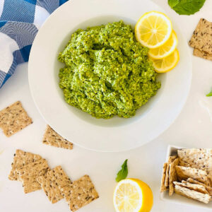cashew basil pesto on a plate with lemon garnish and crackers
