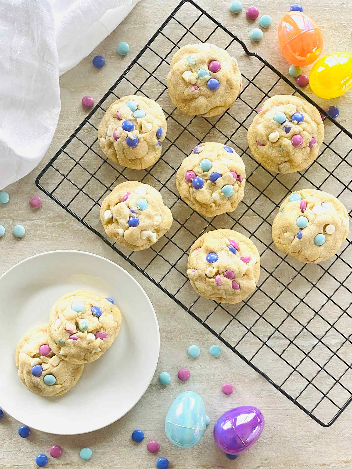 easter m&m cookies on a cooling rack next to colored Easter eggs