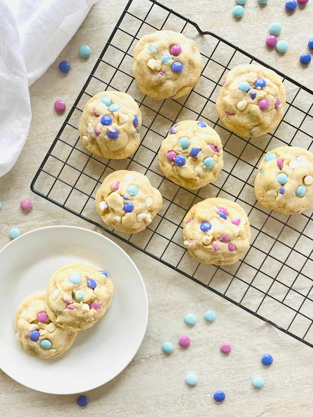m and m easter cookies on a cooling rack next to a plate with cookies