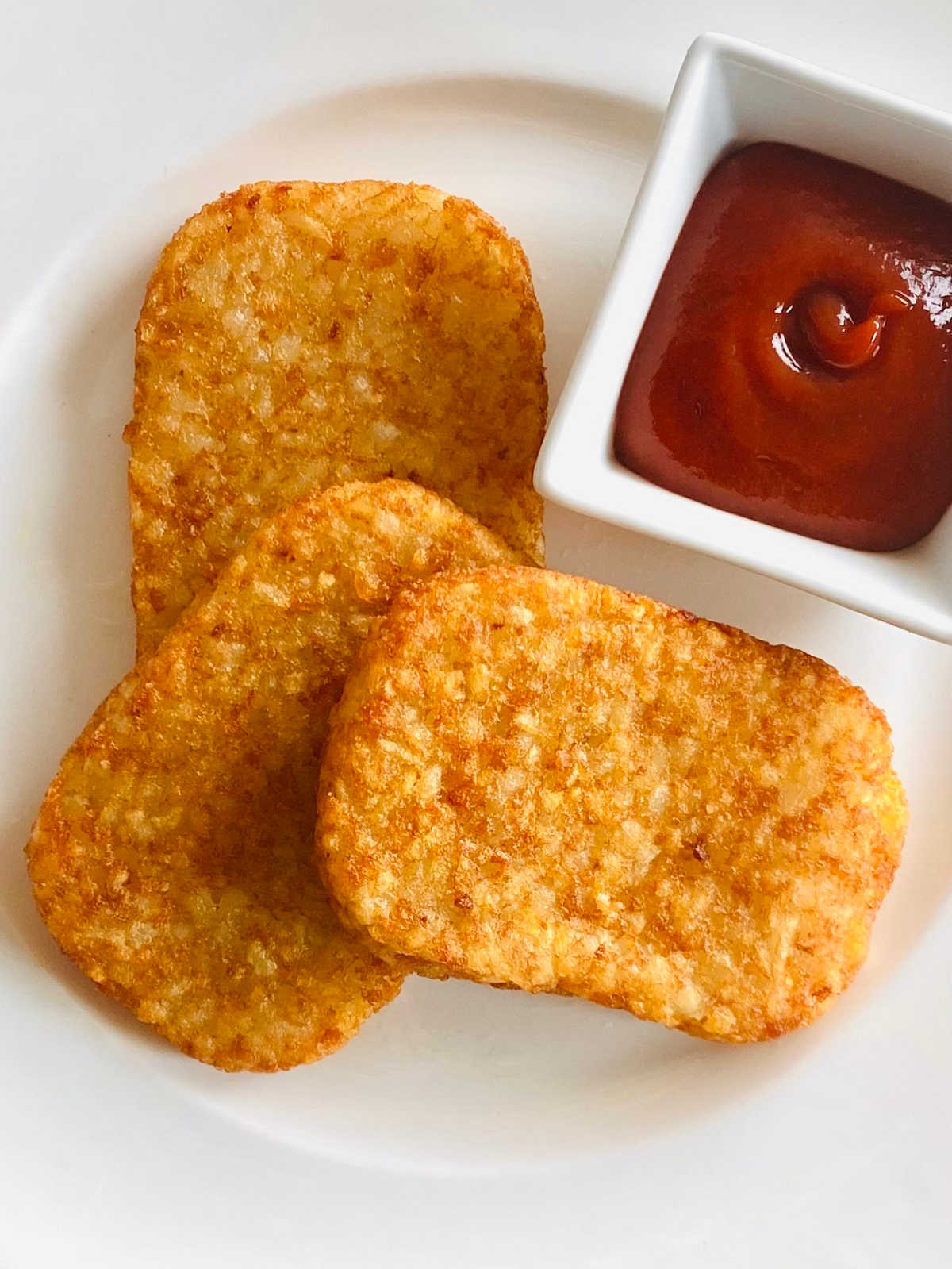 air fryer hash browns on a plate with ketchup