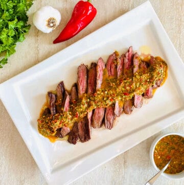 denver steak cut in slices topped with red chimichurri