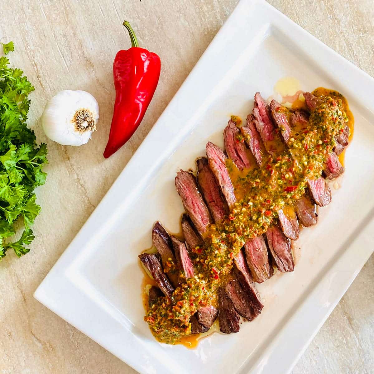 denver steak recipe sliced on a plate with chimichurri