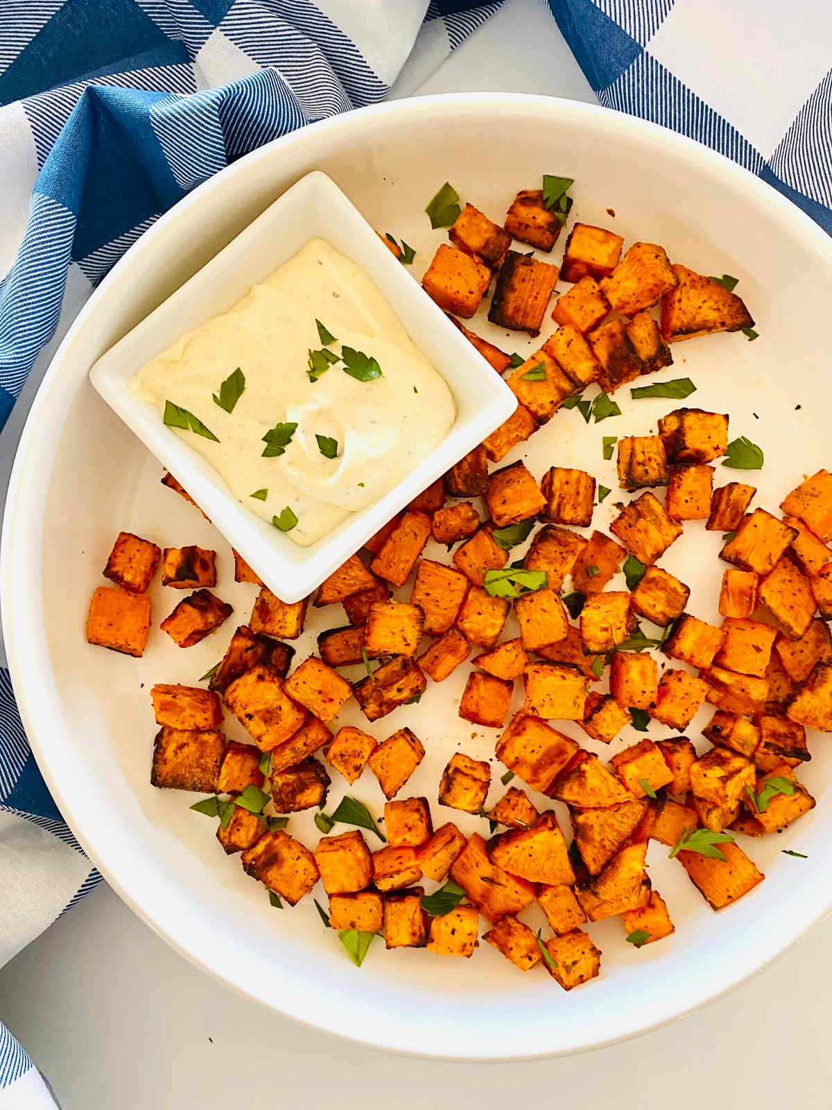 air fryer sweet potato cubes on a plate with a side of dipping sauce.