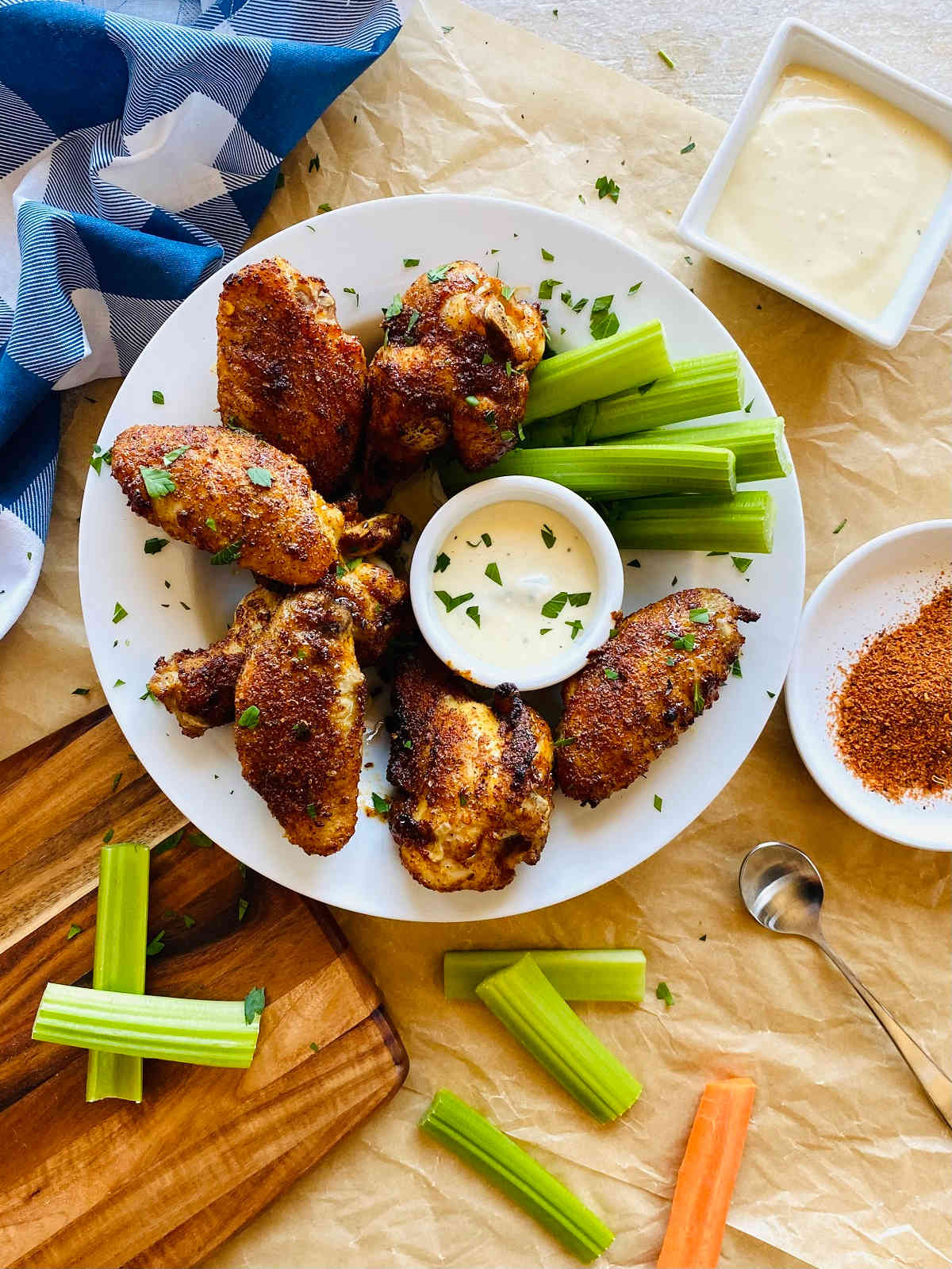 cajun wings on a plate with dish of blue cheese, celery and carrots