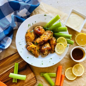 honey garlic lemon pepper sauce wings on a plate with celery, carrots and blue cheese dipping sauce