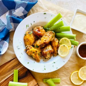 hot honey lemon pepper wings on a plate with celery, carrots and blue cheese dipping sauce