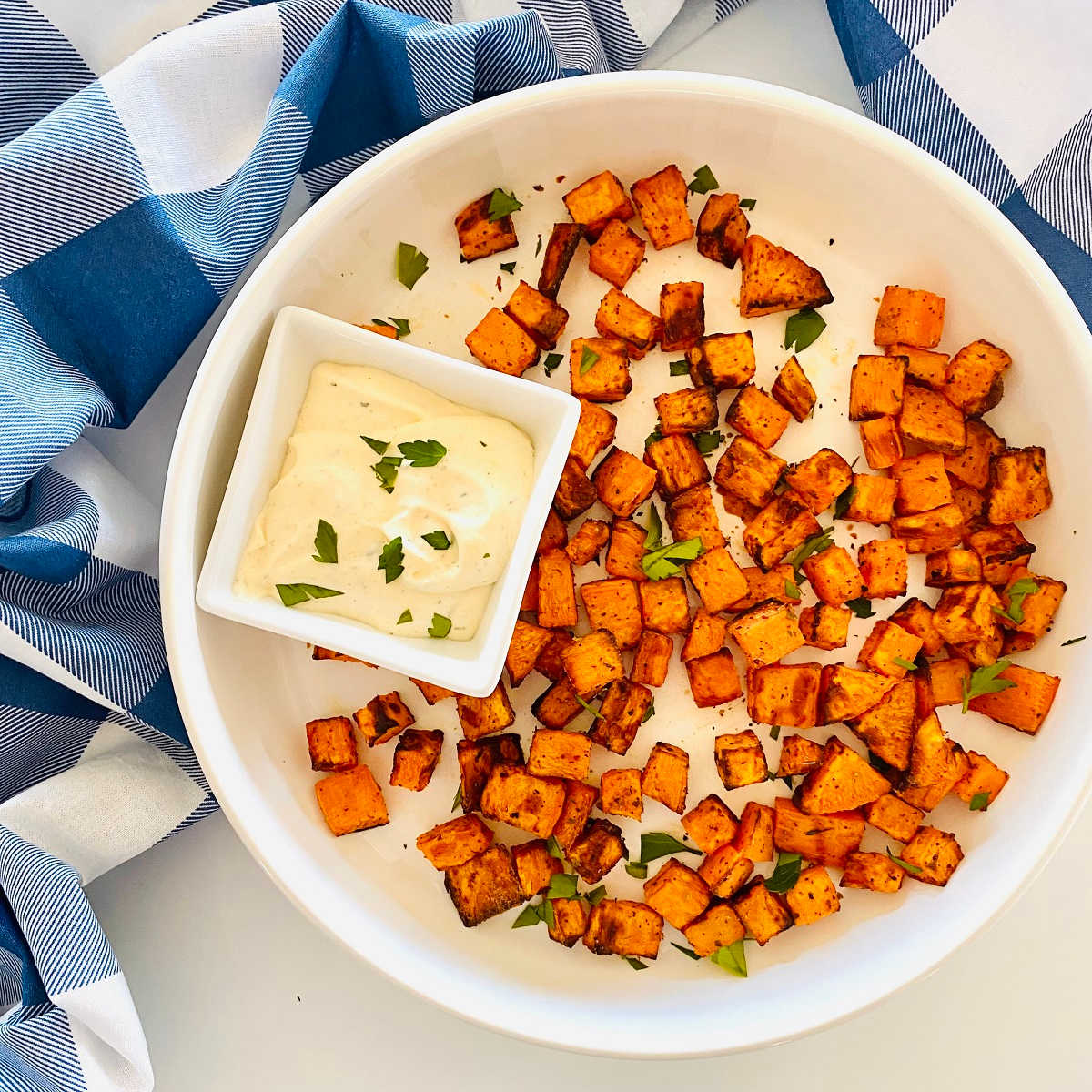 cooked sweet potato cubes on a plate with a side of dipping sauce