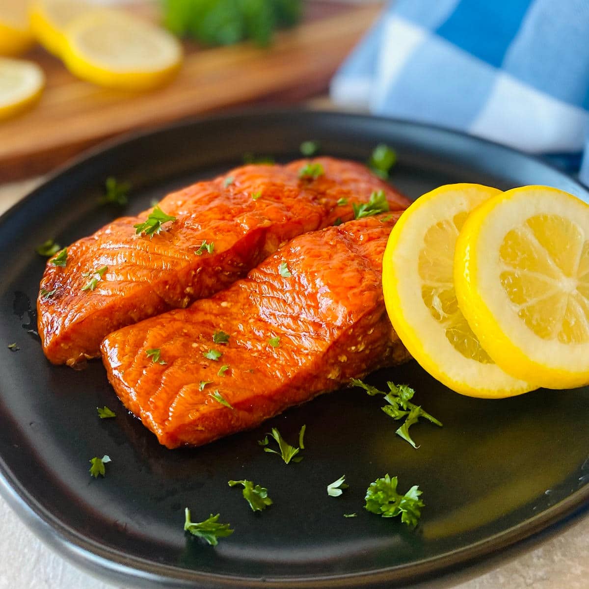 smoked salmon on a plate with sliced lemons and parsley garnish.