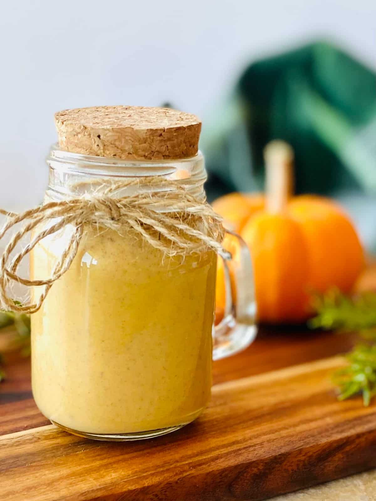 copycat starbucks pumpkin sauce in a jar with a pumpkin in the background.