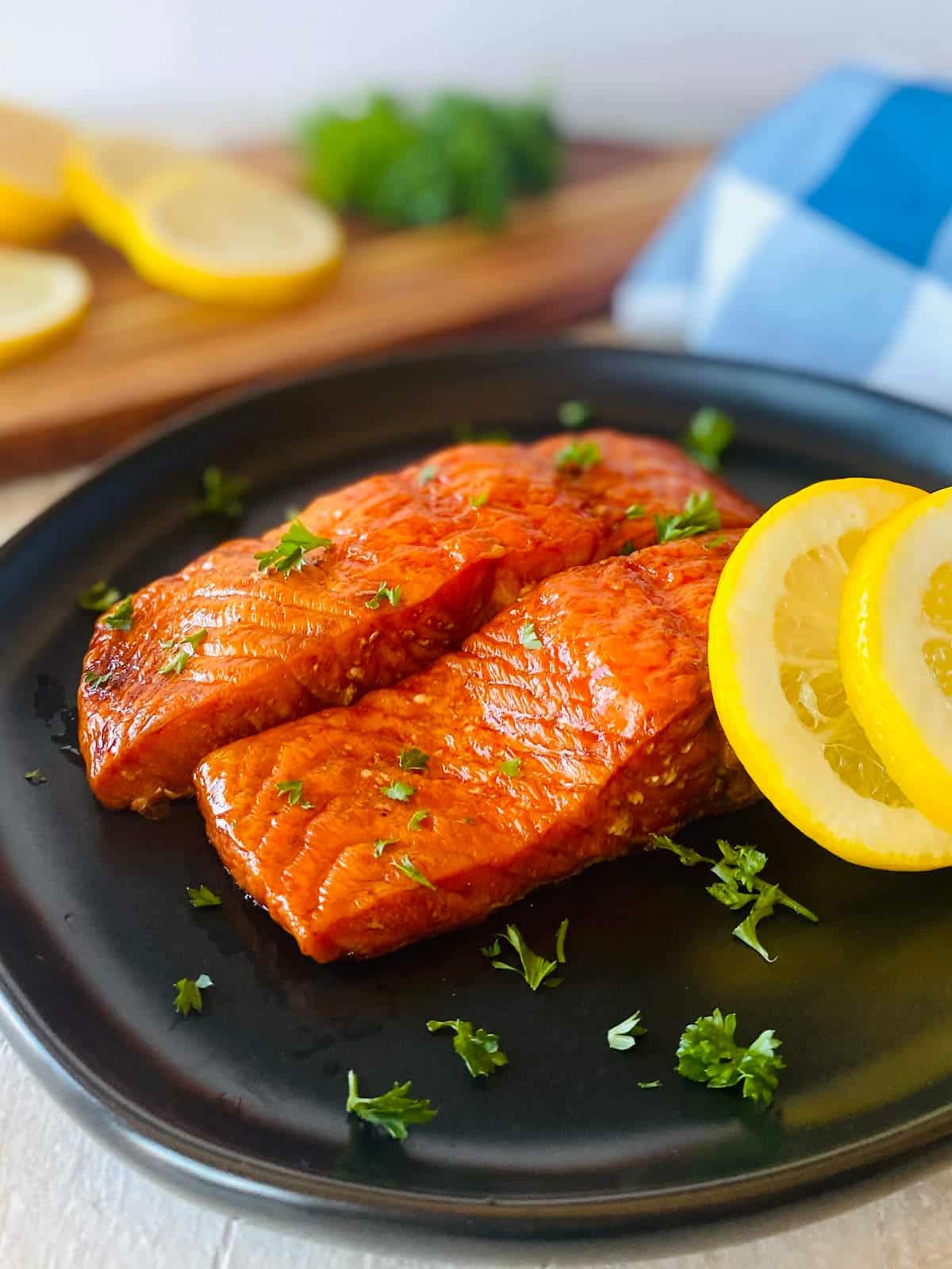 two smoked salmon filets on a plate with sliced lemons.