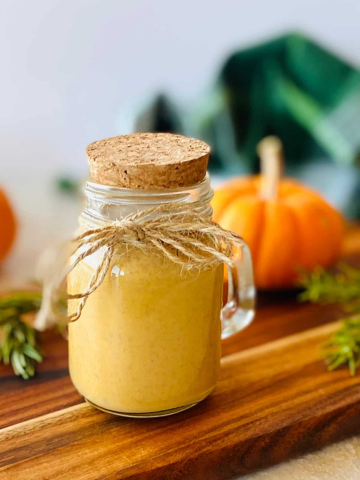 starbucks pumpkin sauce in a jar with a pumpkin and green napkin in the background.