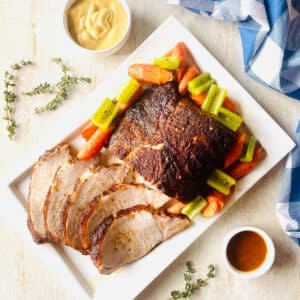 smoked pork loin recipe on plate surrounded by roasted vegetables.
