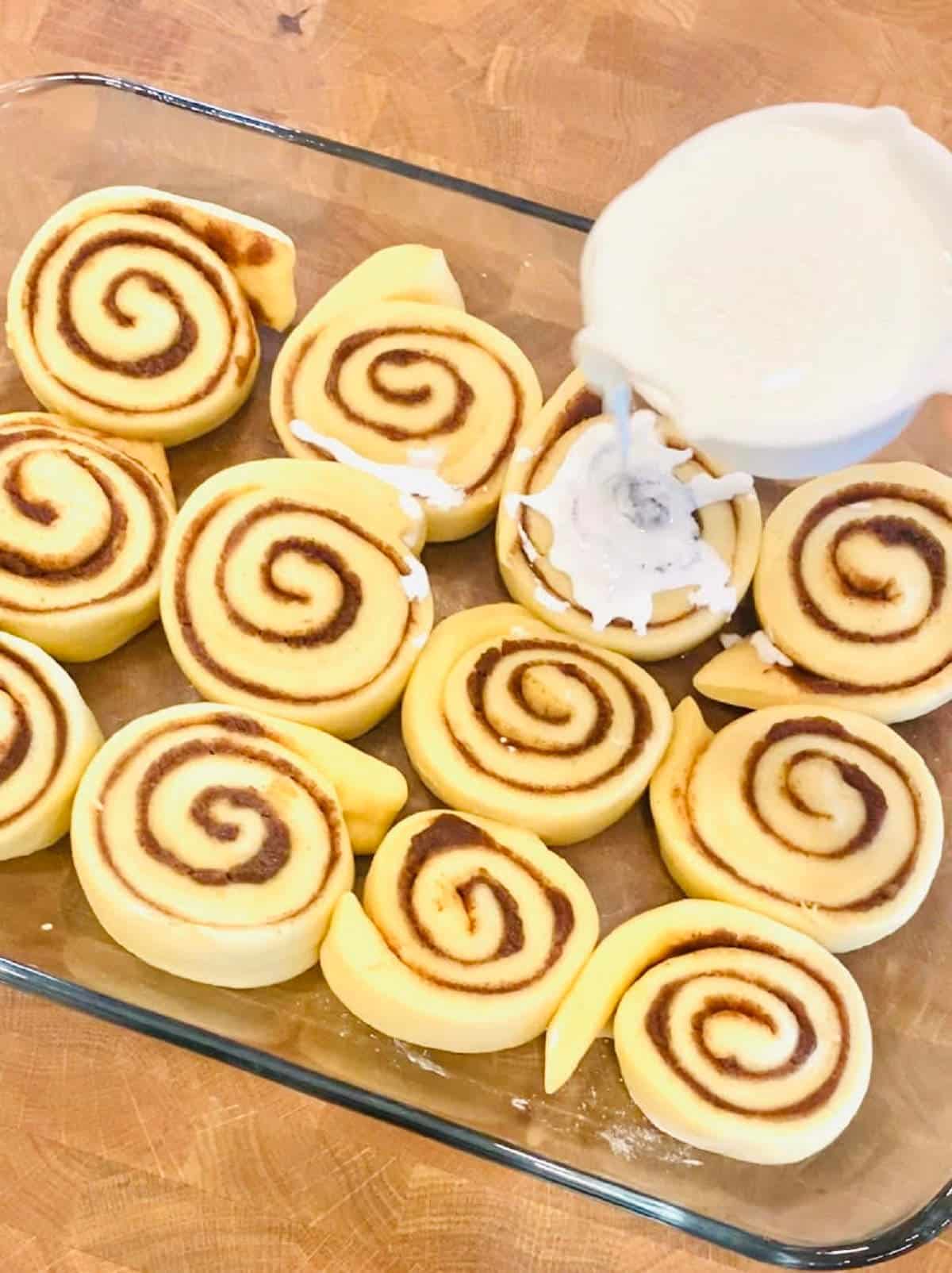 canned cinnamon rolls with heavy cream being poured on top.