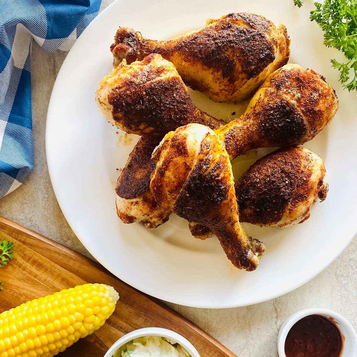 Smoked Chicken Legs drumsticks on plate with corn and coleslaw sides.