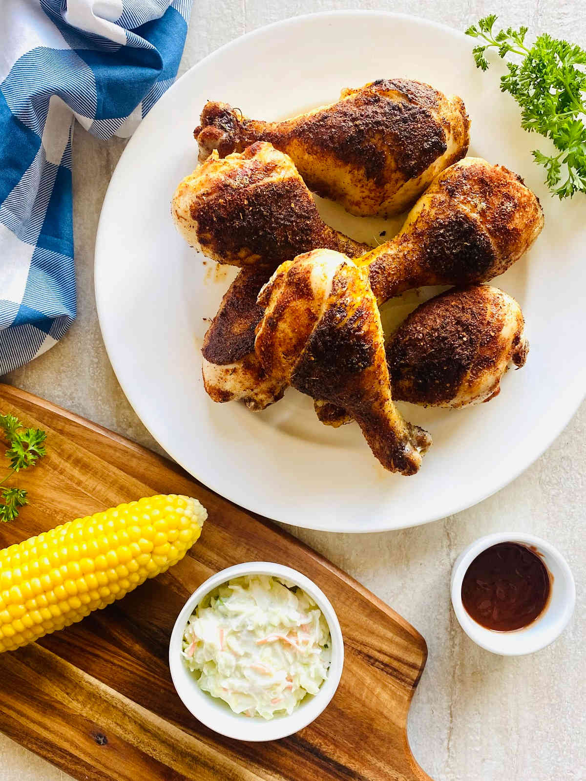 Smoked Chicken drumsticks on plate with corn, coleslaw and bbq sauce.