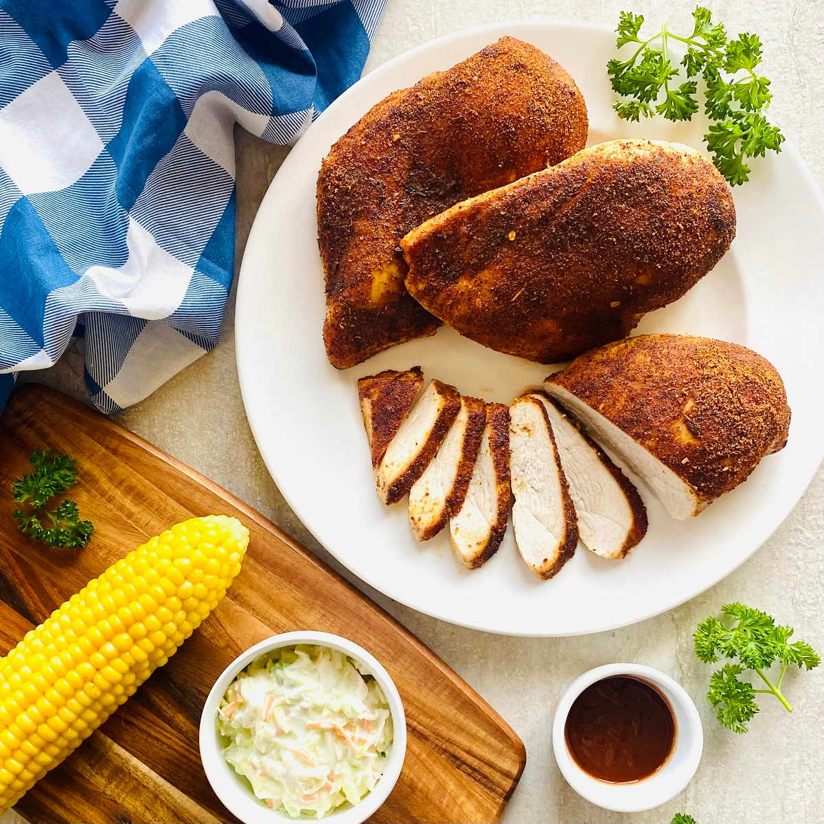pellet grill chicken breast on a plate with corn and coleslaw.