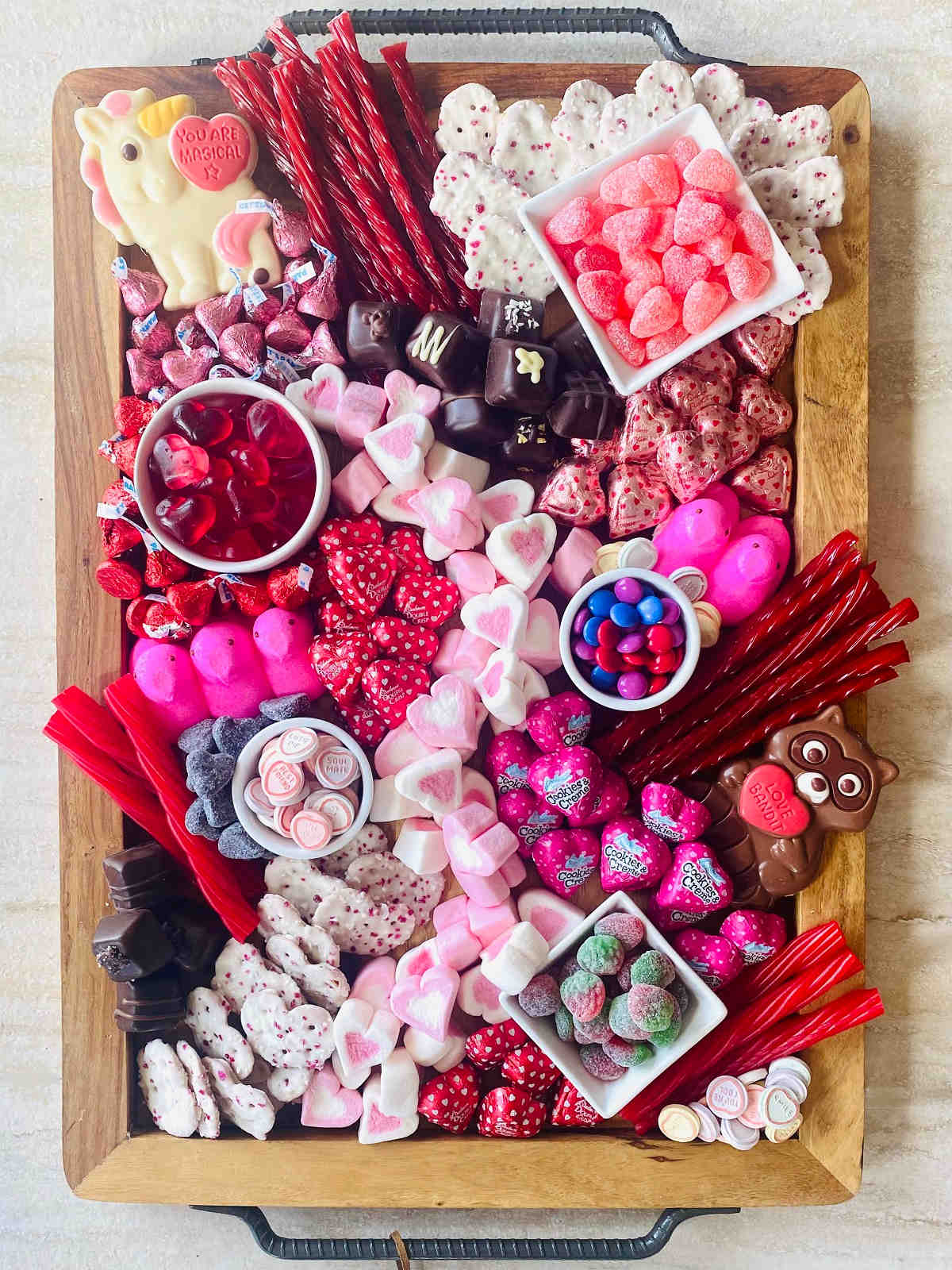 valentine’s day charcuterie board with different colored valentine candy.